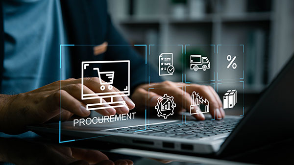 Hands typing on a laptop with a digital overlay showing icons related to procurement, including a shopping cart, checklist, truck, factory, and boxes.
