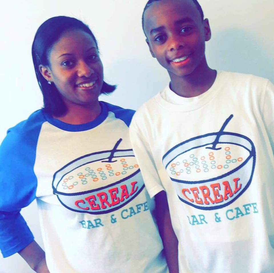 Two people wearing matching t-shirts that say "Cereal Bar & Cafe" with a graphic of a bowl of cereal.
